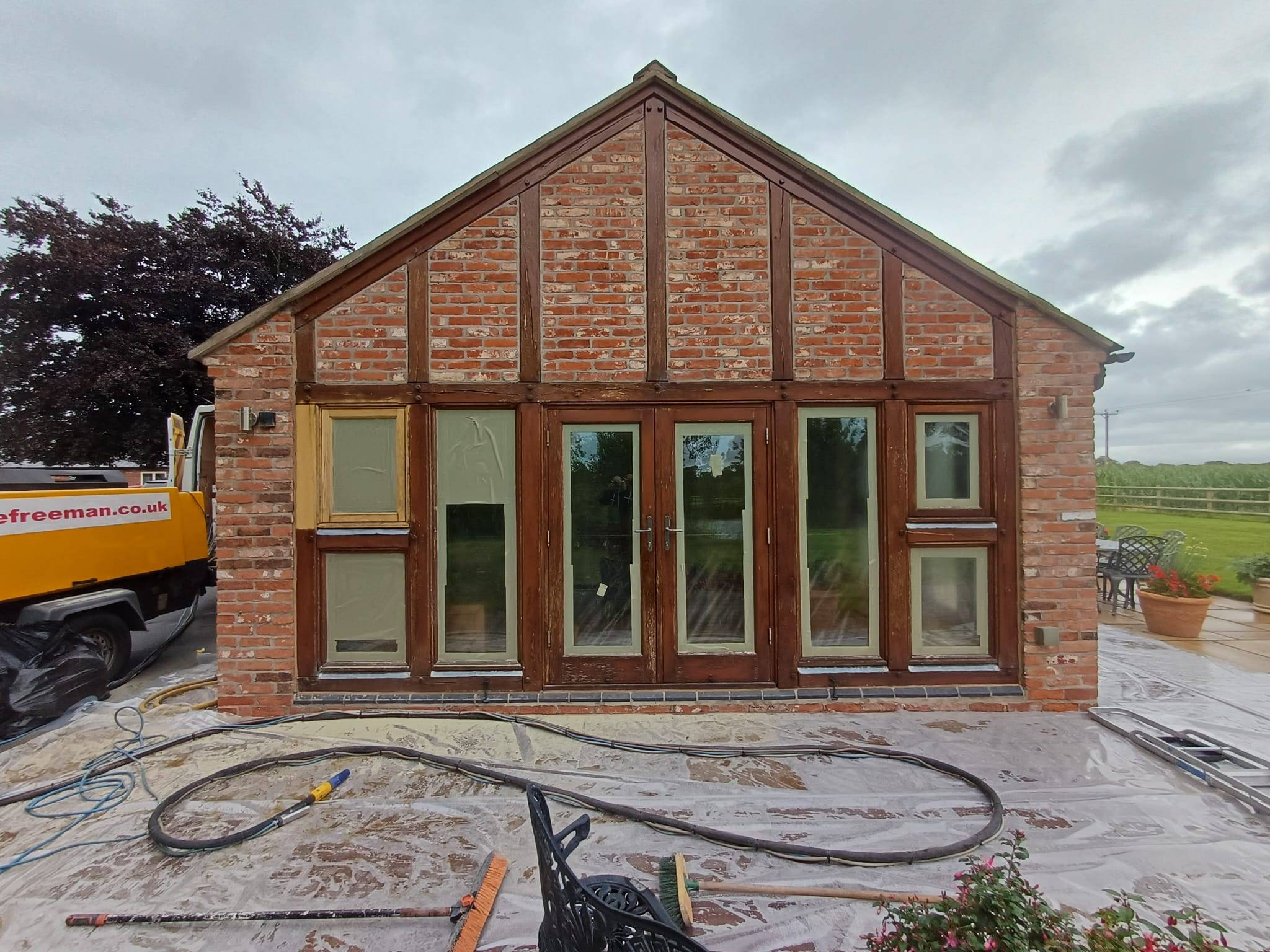 Timber outbuilding before restoration with dark, tired staining and weathered exterior