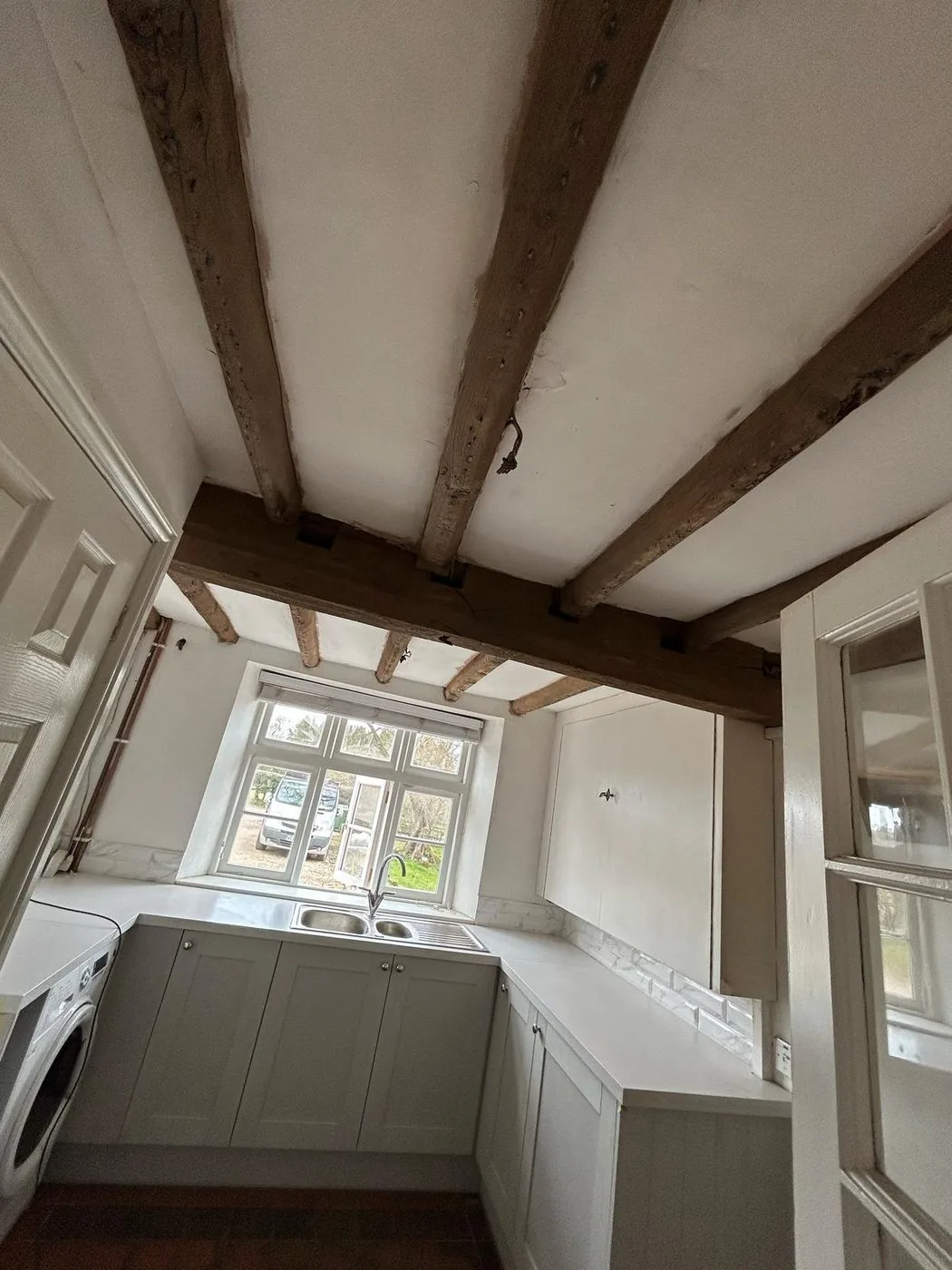Restored oak kitchen beams showing brighter natural grain above shaker cabinetry