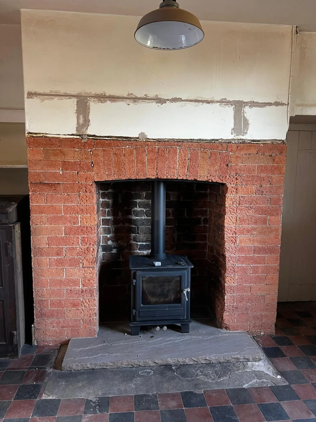 Clean red Victorian brick surround restored around the wood-burning stove