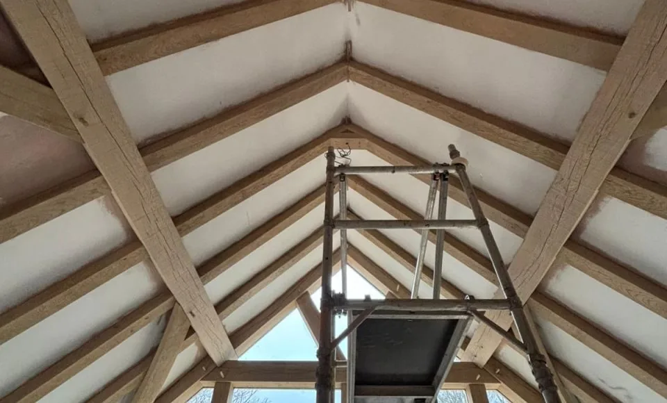 Restored oak A-frame roof structure with a lighter clean finish and natural beam grain visible