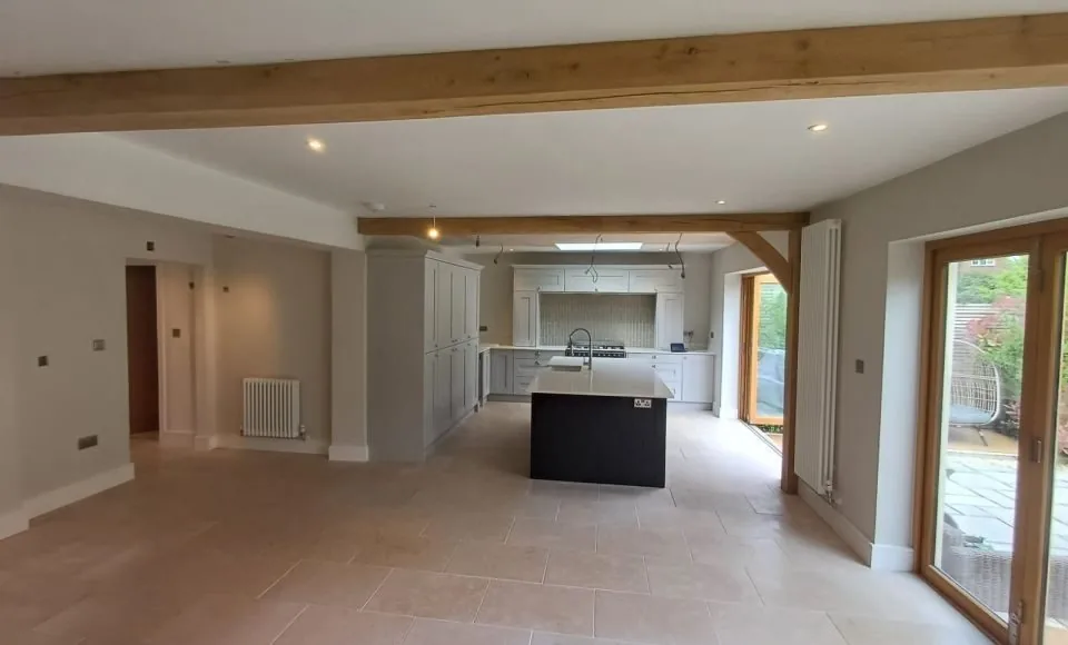 Open-plan kitchen with brighter exposed oak beams and clean tiled floor following careful restoration