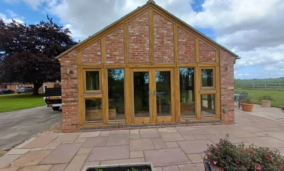 Front of orangery with bright natural timber framing and clean reflective glazing after restoration