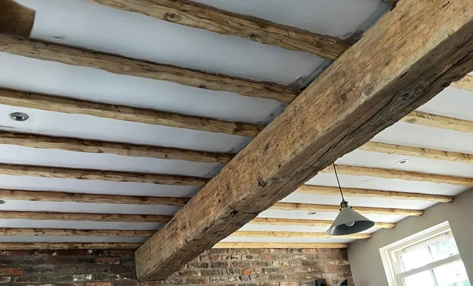 Naturally toned restored timber beams framing a rustic fireplace interior