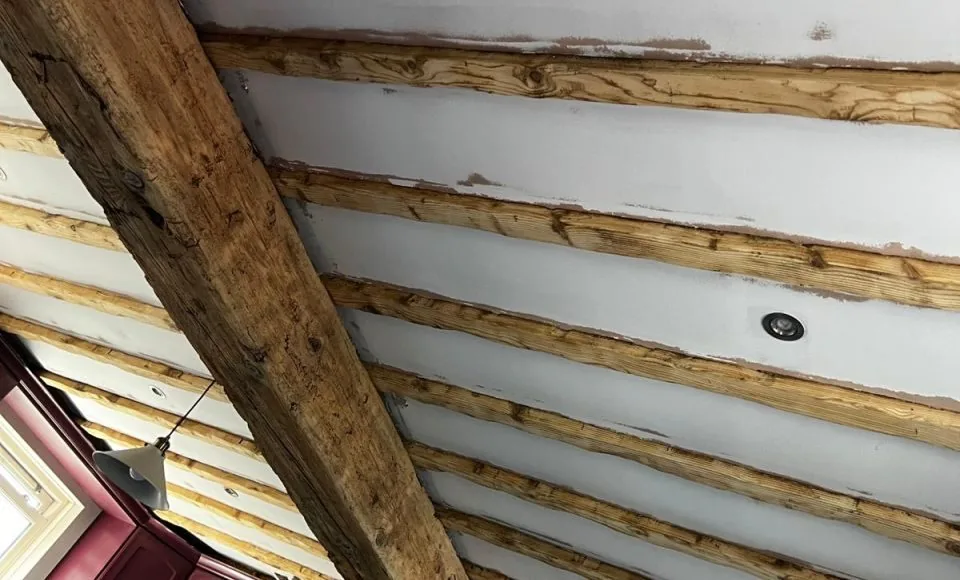 Clean natural timber beam detail showing restored grain beside the fireplace