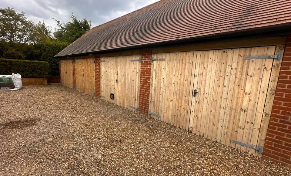 Restored brick garage showing clean pale timber doors with original metal hinges visible