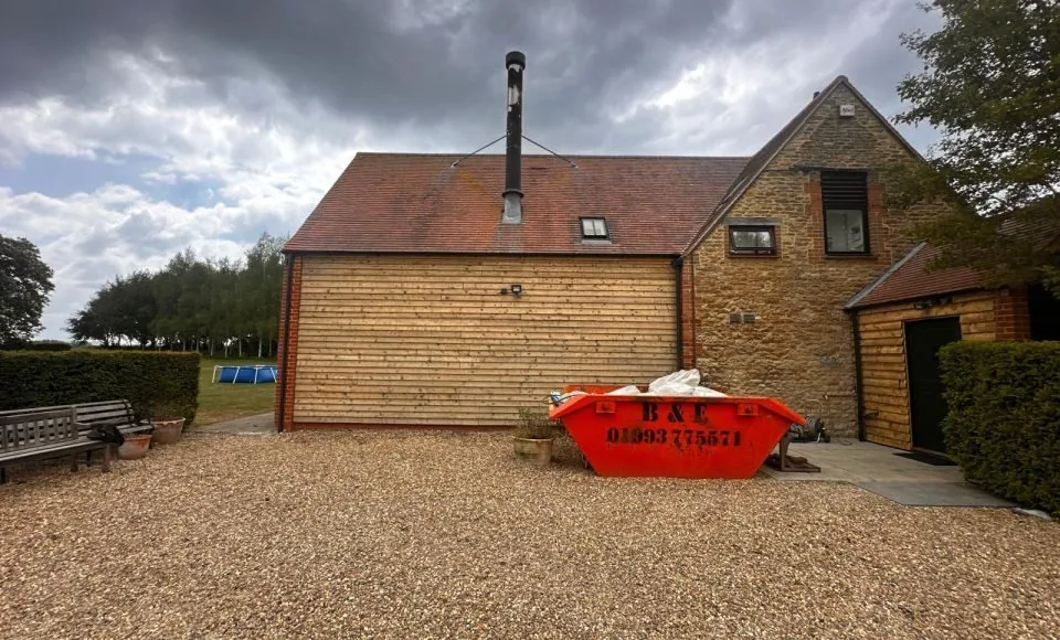 Wide restored outbuilding elevation with bright timber cladding beside a stone-faced gable