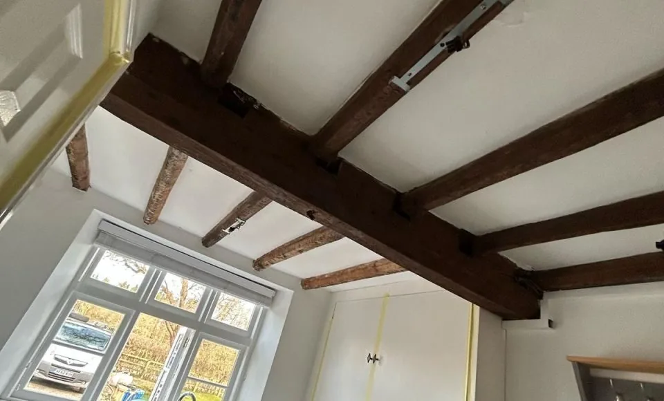 Freshly restored light oak kitchen beams complementing modern cabinets and worktops