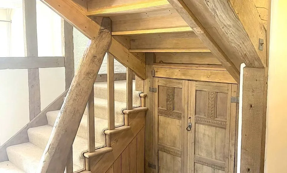 Restored oak staircase and cupboard showing lighter grain after controlled finish removal