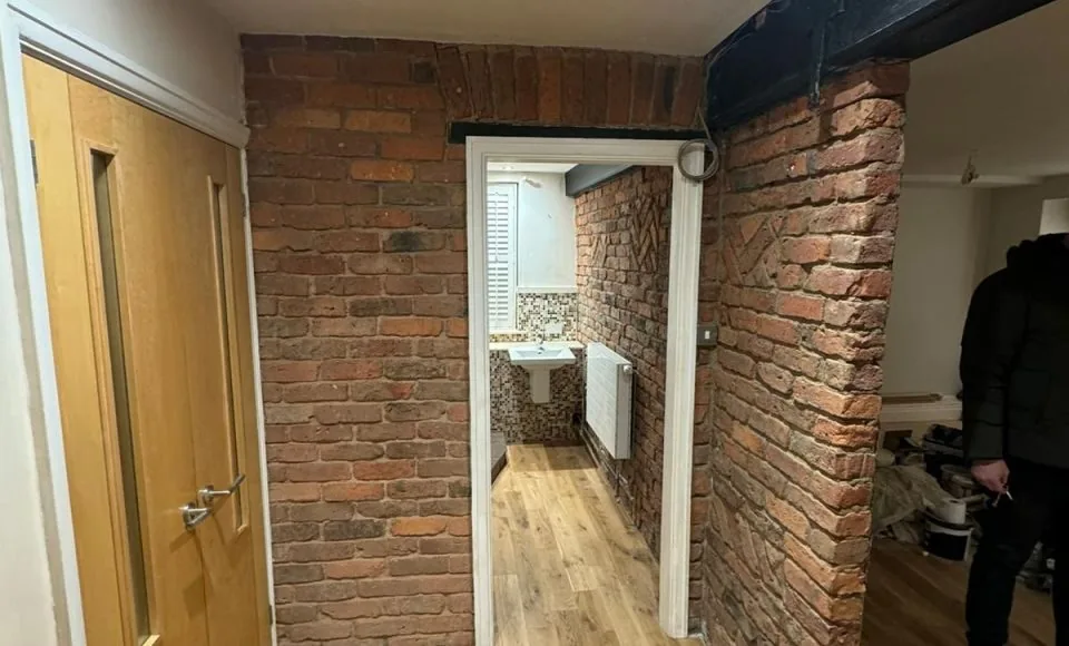 Clean exposed red brick feature wall beside a contemporary bathroom after paint removal