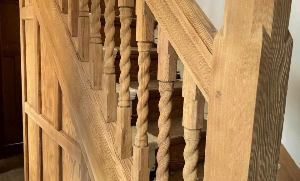 Restored timber staircase with warm grain, carved newel post and twisted balusters