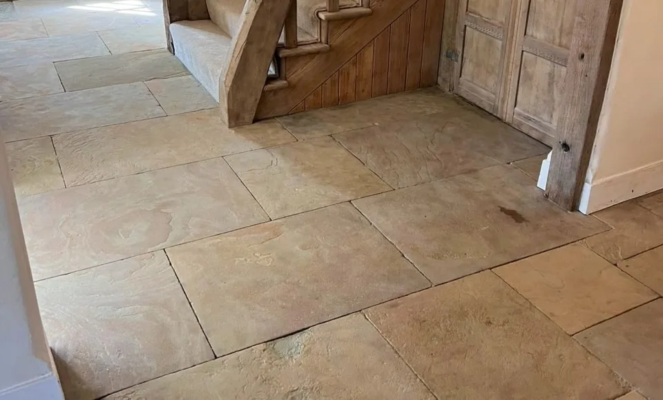 Clean restored flagstone floor with brighter natural tones and defined stone texture beside the staircase