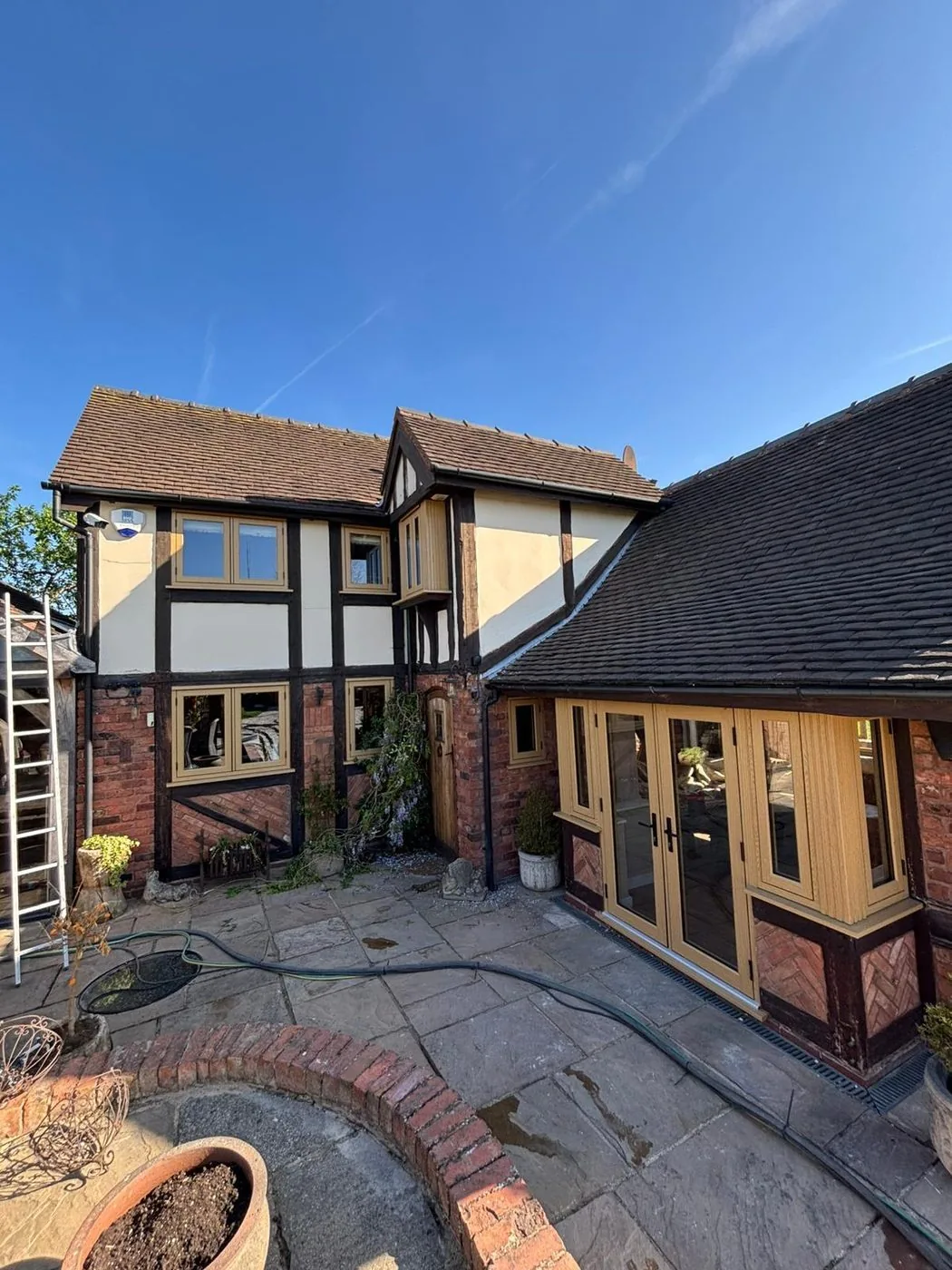 Restored Tudor oak framing with brighter grain and clean brick surrounds after gentle treatment
