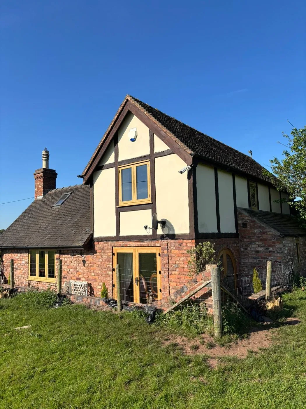 Cleaned twin-gabled outbuilding with renewed timber detail and refreshed masonry setting