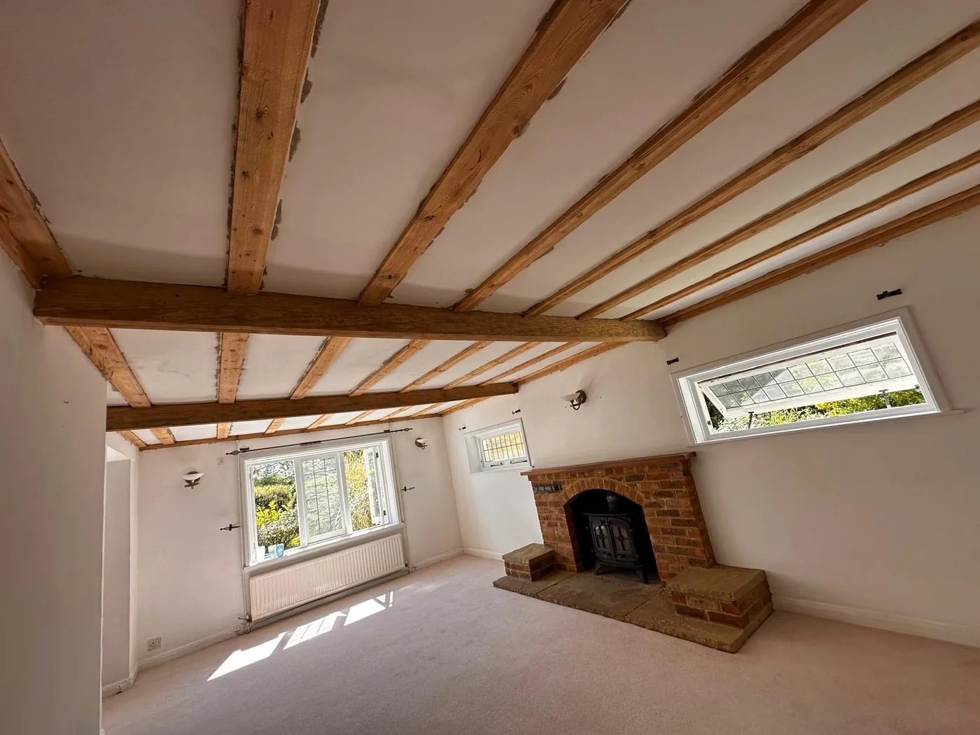 Clean restored cross beams and ceiling joists framing the cottage fireplace and finished living space throughout