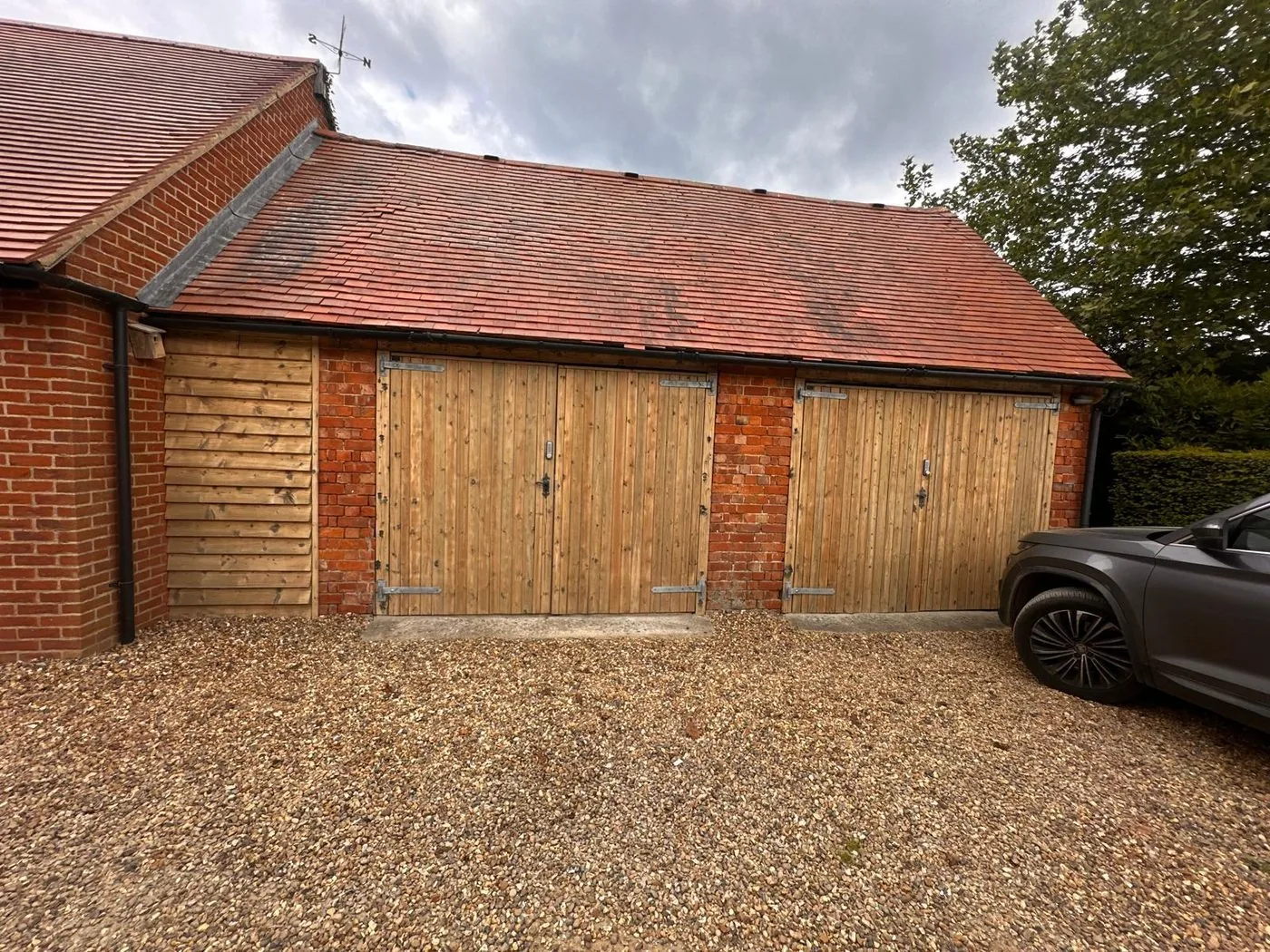 Rural estate outbuilding doors with a cleaner, lighter natural timber appearance after restoration