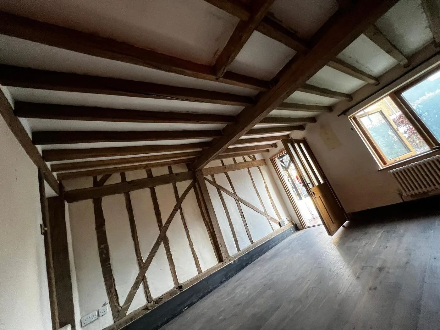 Restored Tudor oak ceiling beams showing a cleaner warm timber tone and preserved historic character