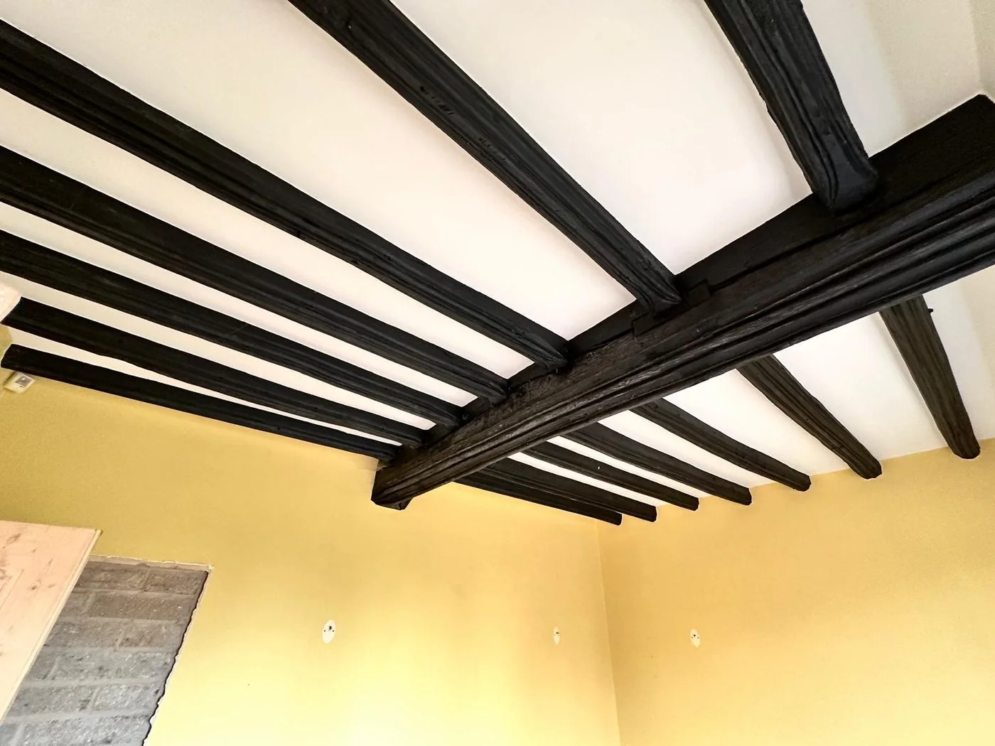 Historic oak ceiling beams before restoration with dark stain and painted surface build-up