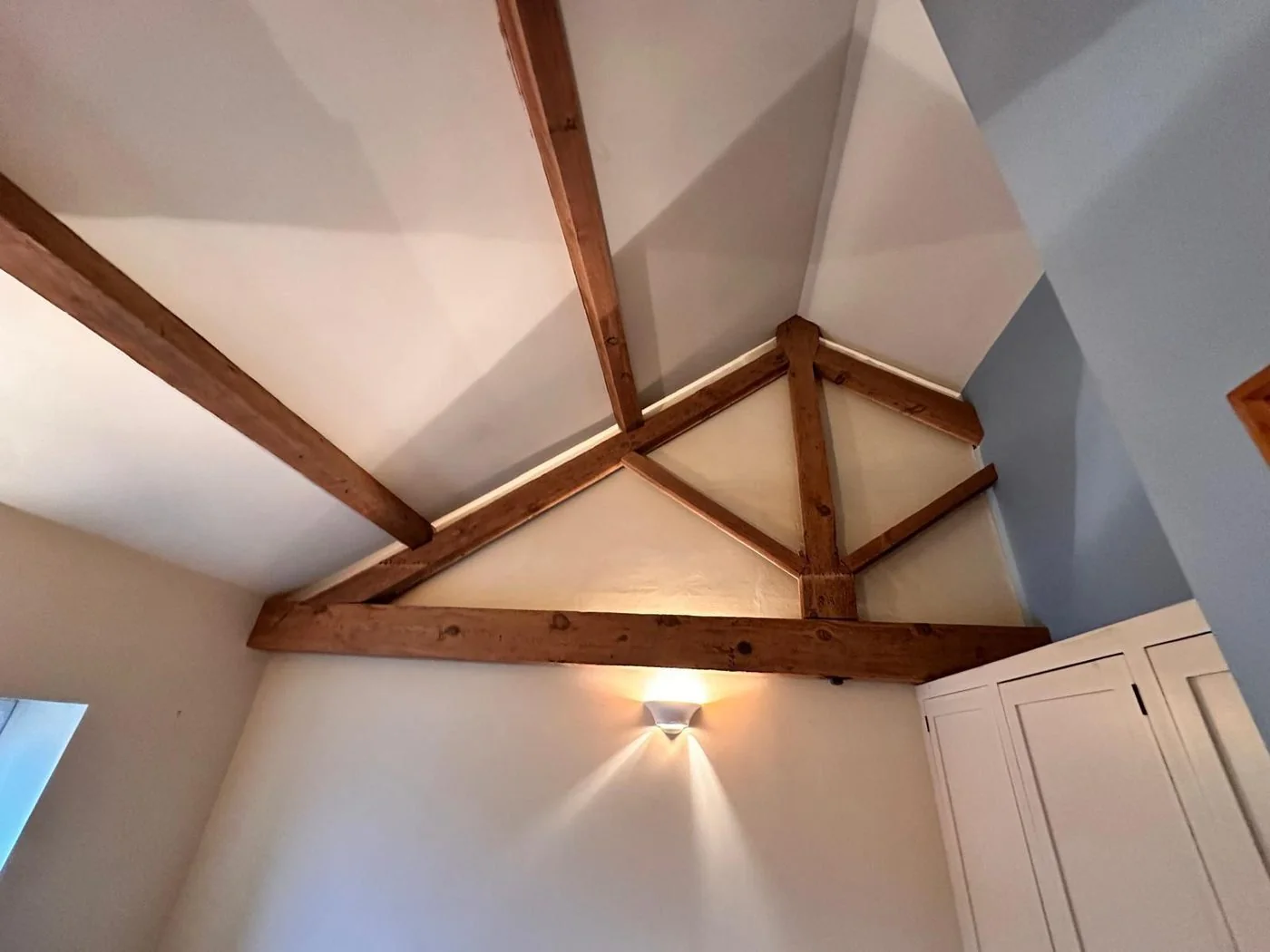 Exposed ceiling beams after restoration with natural timber contrasting against white loft finishes