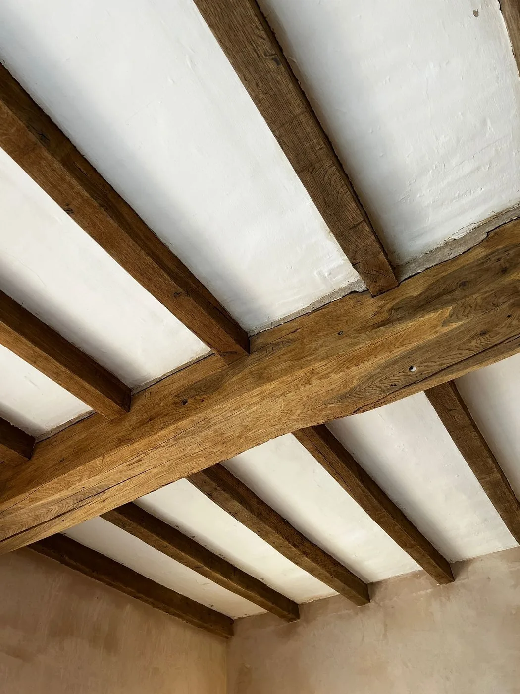 Clean natural oak beam surfaces restored across a characterful period ceiling