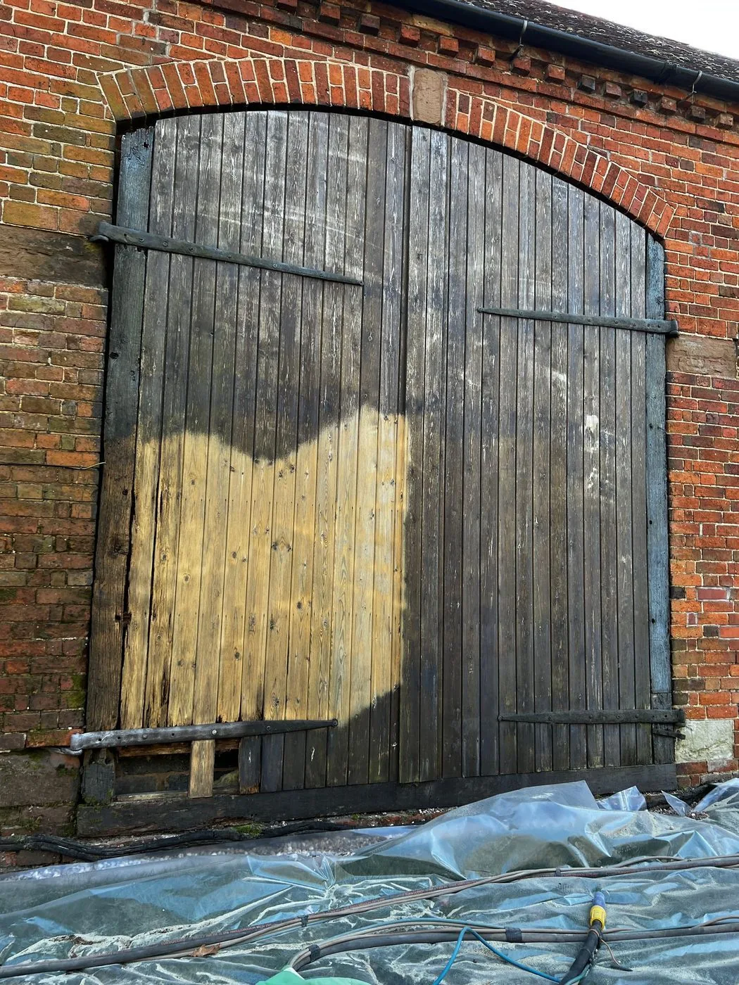 Cleaned arched barn door showing warmer timber tone and preserved traditional detailing