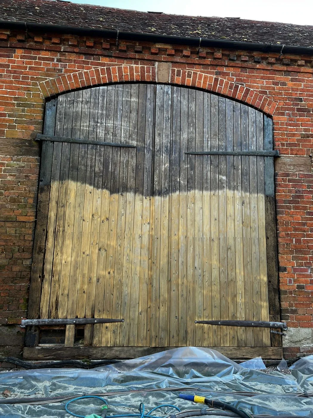 Refreshed barn entrance with brightened timber door framed by historic brick masonry