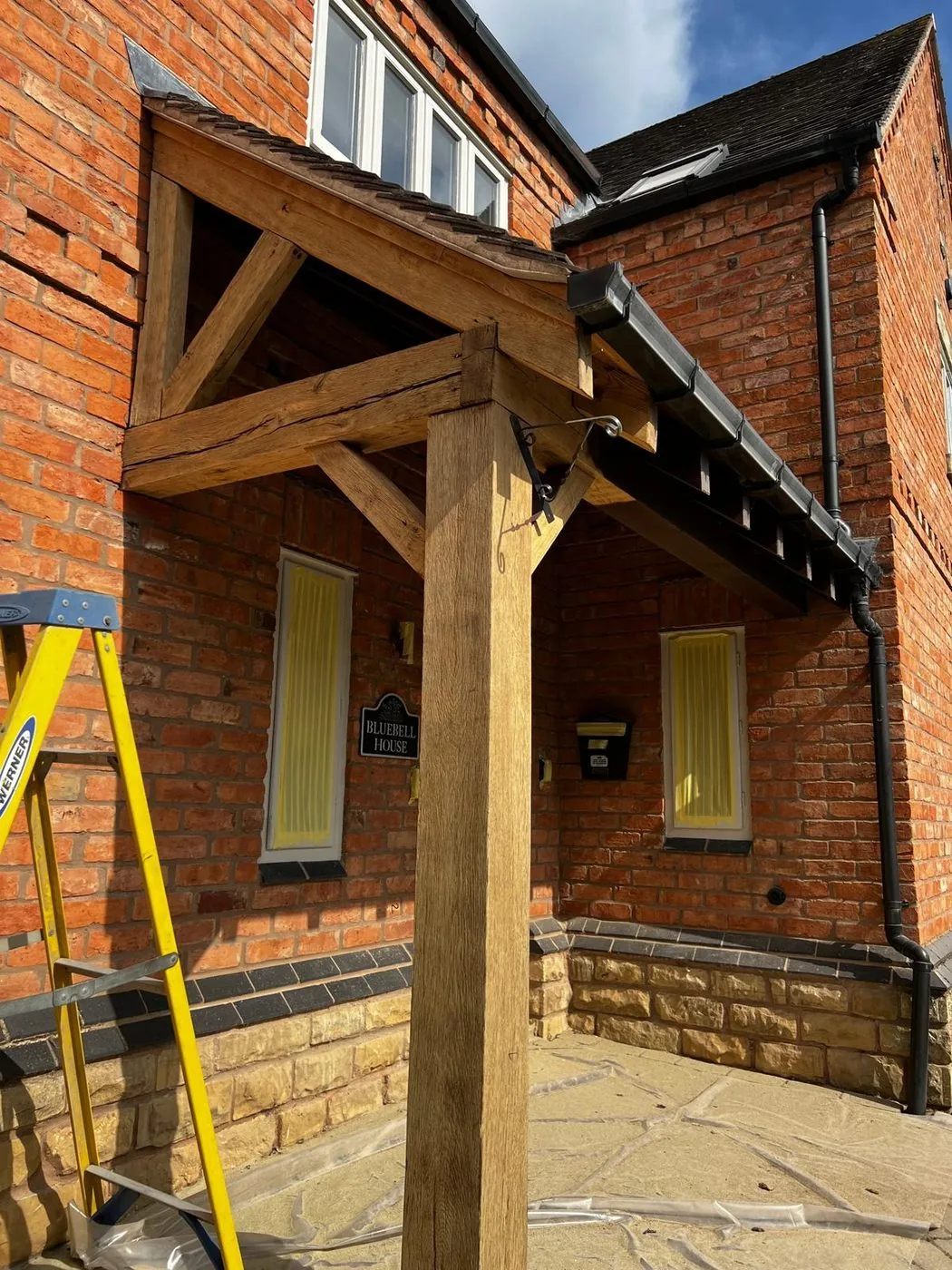 Freshly cleaned oak porch frame with brighter grain across restored beams and posts