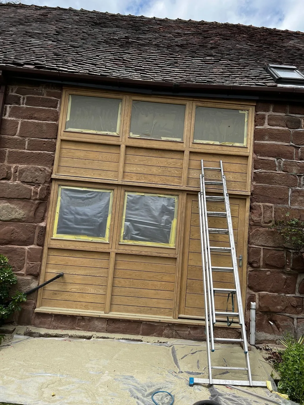 Restored oak door and window frames with clean grain and a warm stained finish beside sandstone walls