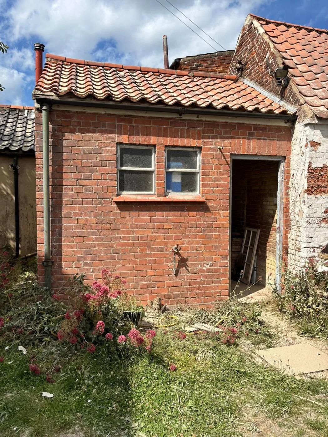 Restored red brick outbuilding wall with paint removed and masonry detail clearly revealed