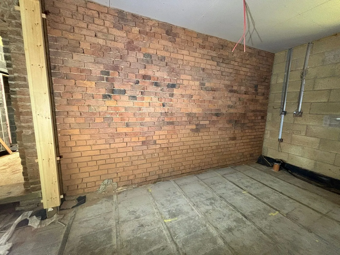 Restored interior brick feature wall with cleaner warm red and multi-toned masonry revealed after gentle surface treatment