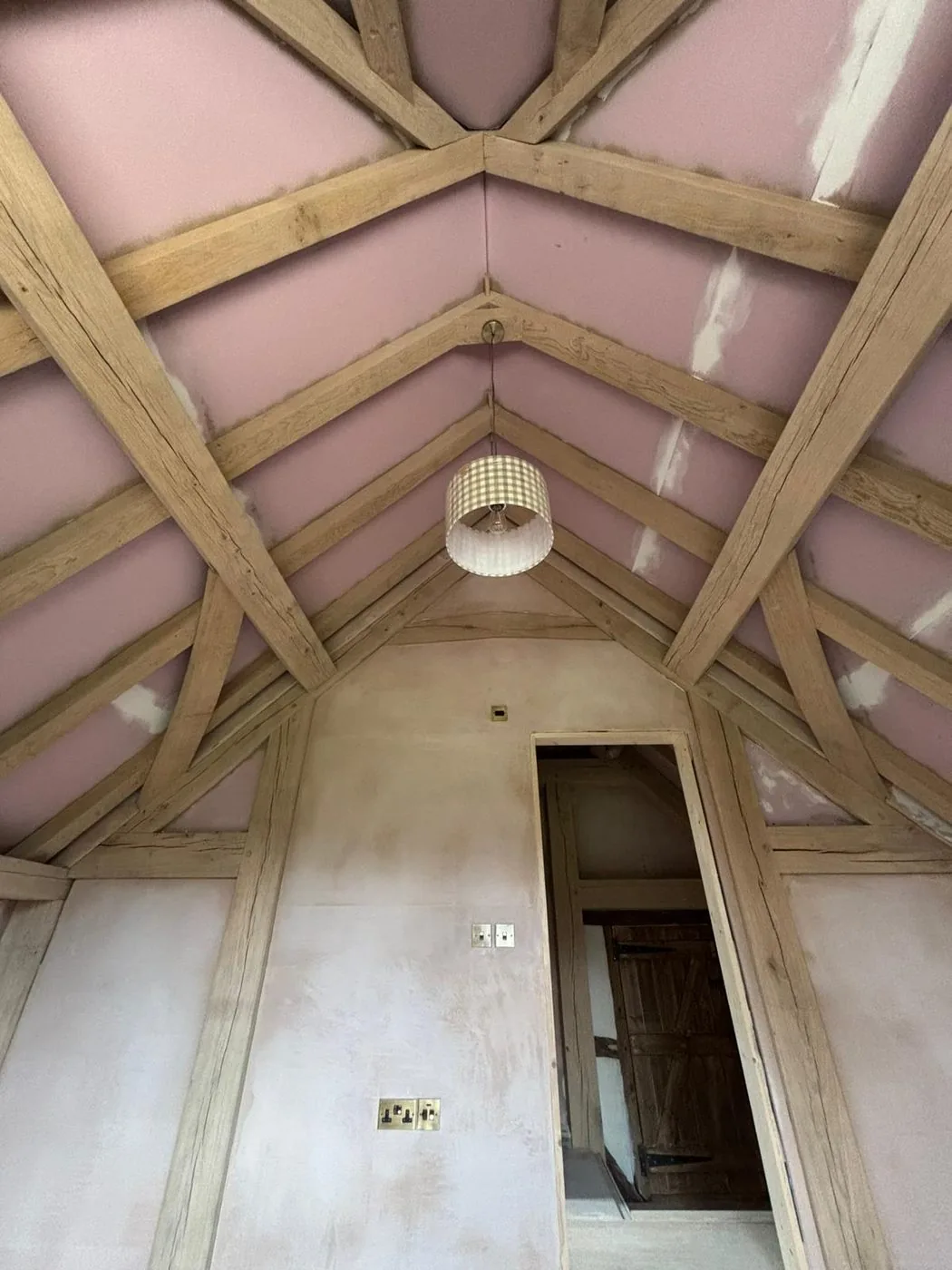Restored oak barn frame with clean golden grain contrasting against fresh pale plaster walls