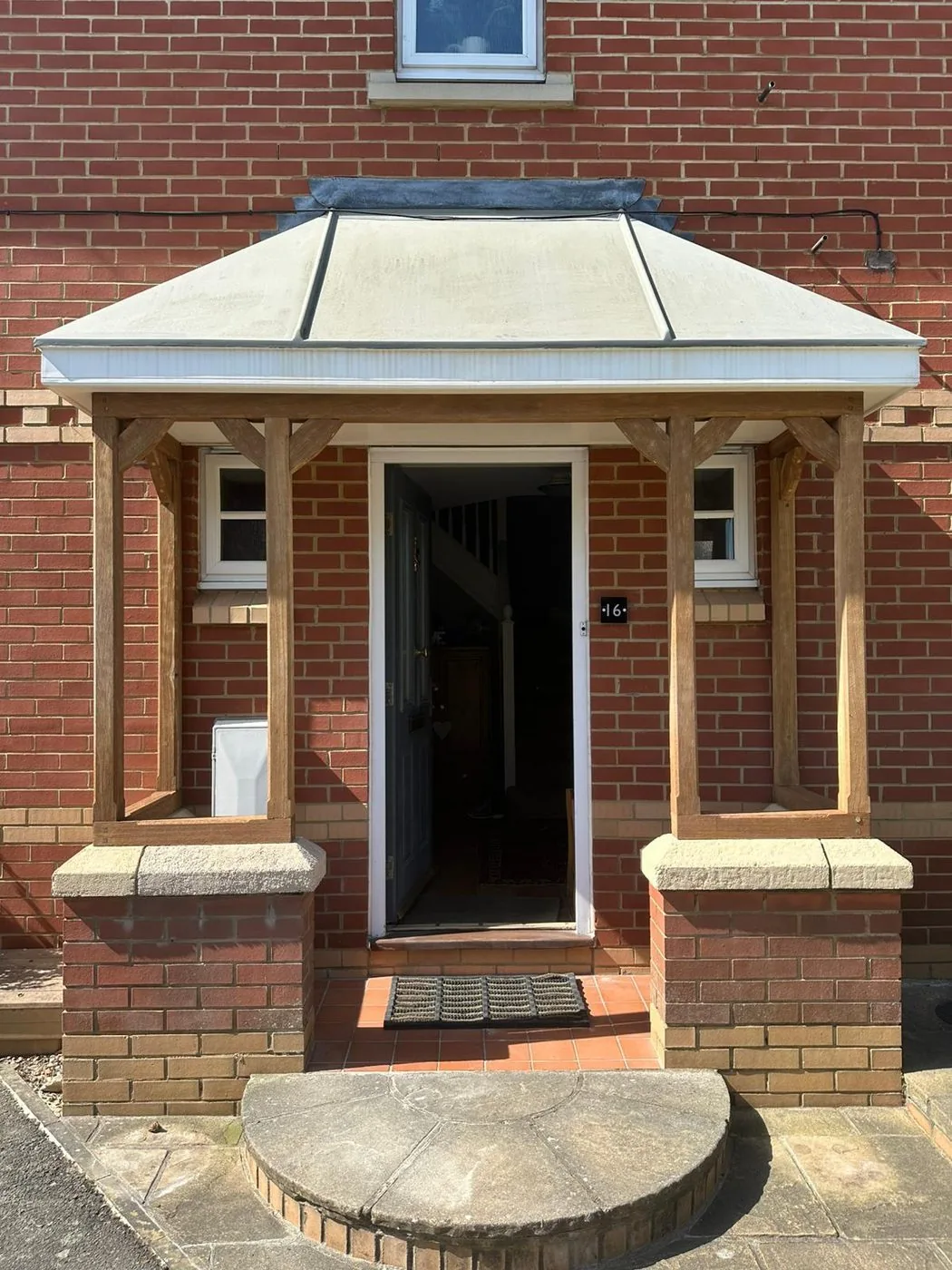Restored wooden porch canopy with clean warm oak posts and decorative brackets
