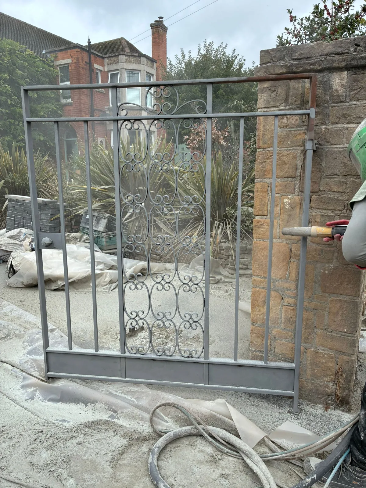 Controlled blast cleaning removing failing paint from steel gate rails and scrollwork