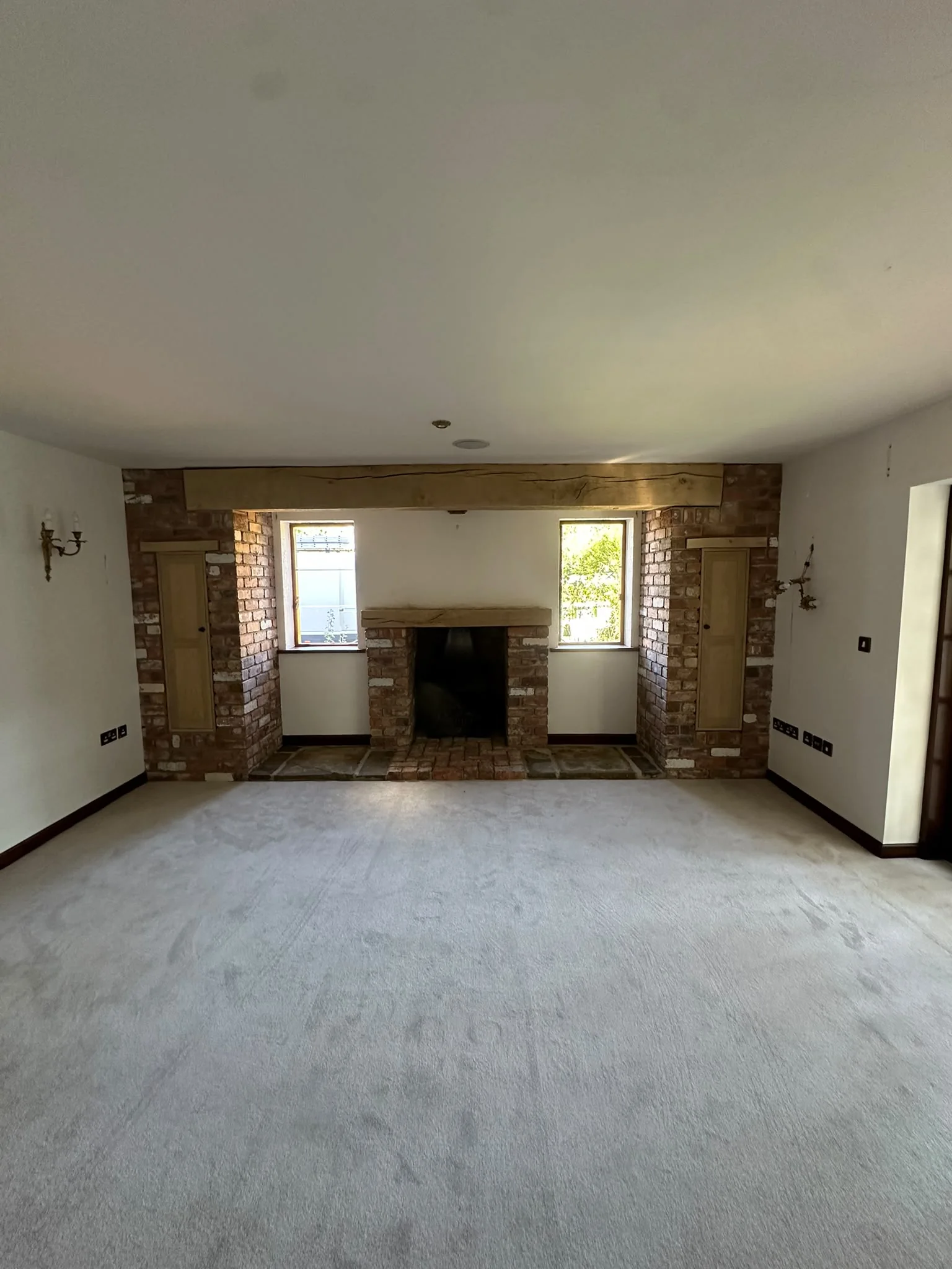 Fireplace feature after restoration showing exposed brickwork and natural timber beam detail